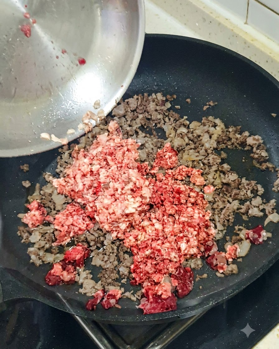 Cebolla roja picada siendo añadida a una sartén que contiene carne picada dorada.