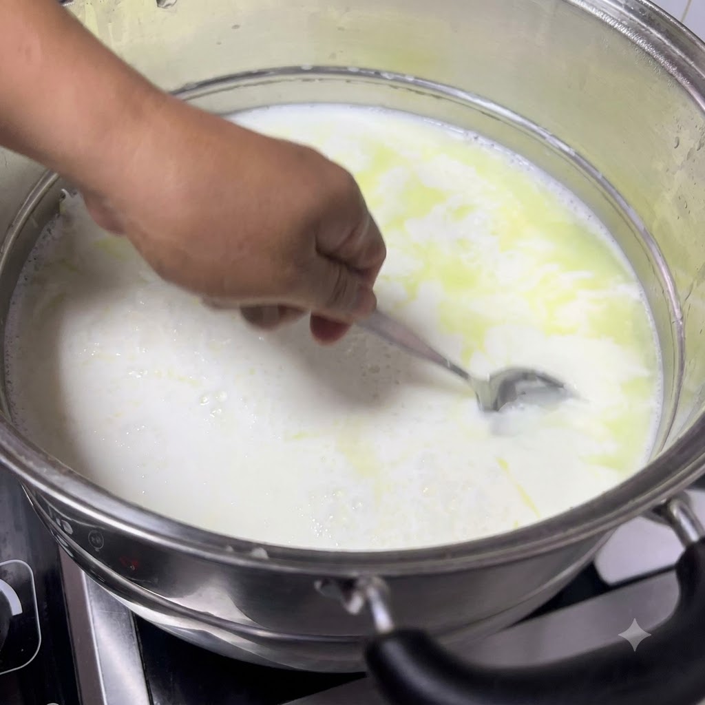 Una cuchara sacando leche cuajada de la olla, mostrando cuajados blancos y suaves que se separan del suero amarillento.