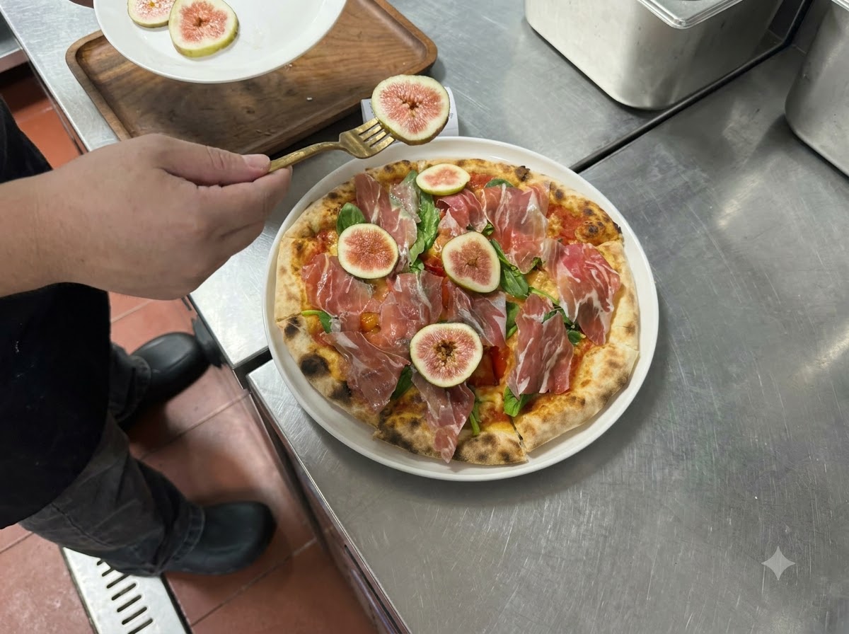 Rodajas de higos frescos y prosciutto colocándose sobre la pizza horneada con un tenedor.