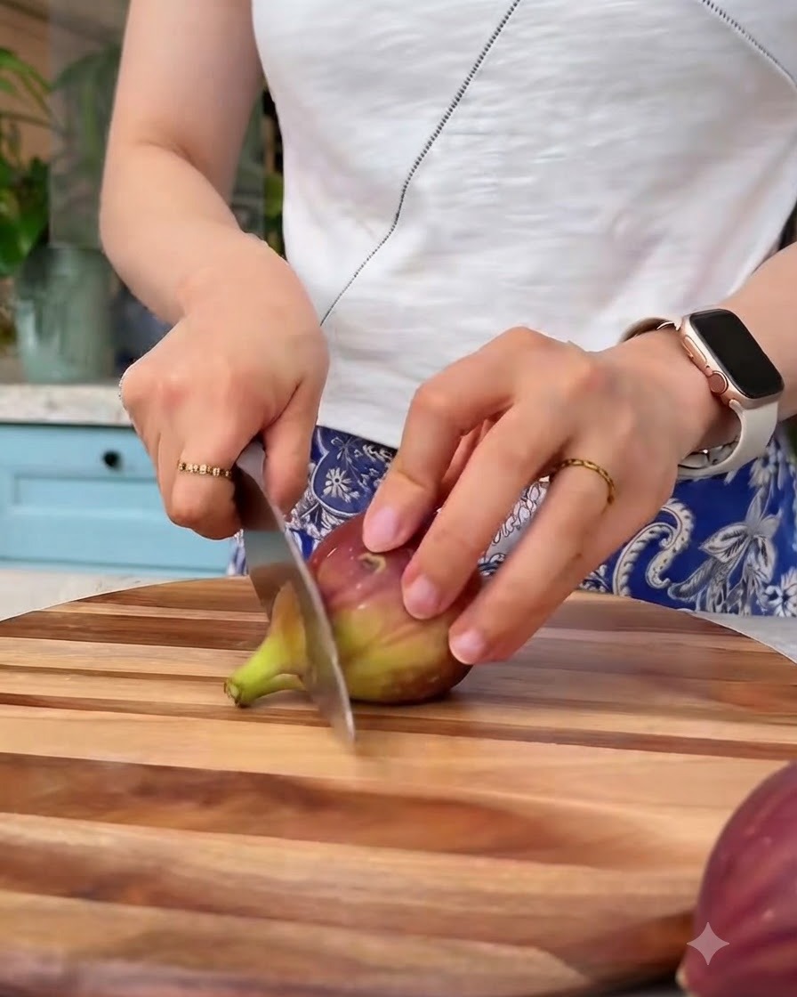 Higos frescos cortados en trozos pequeños con un cuchillo sobre una tabla de cortar de madera.