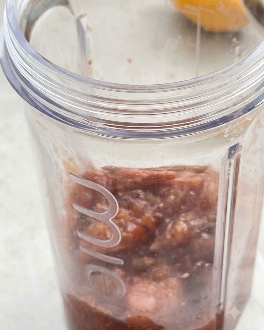 Mezcla de higos cocinados y crema de coco vertida dentro de un vaso de licuadora transparente.