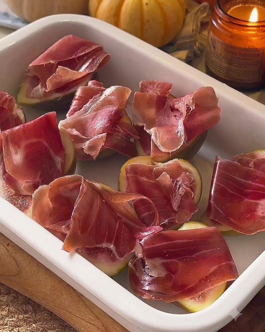 Higados ensamblados y cubiertos con prosciutto dispuestos en una fuente blanca para hornear.