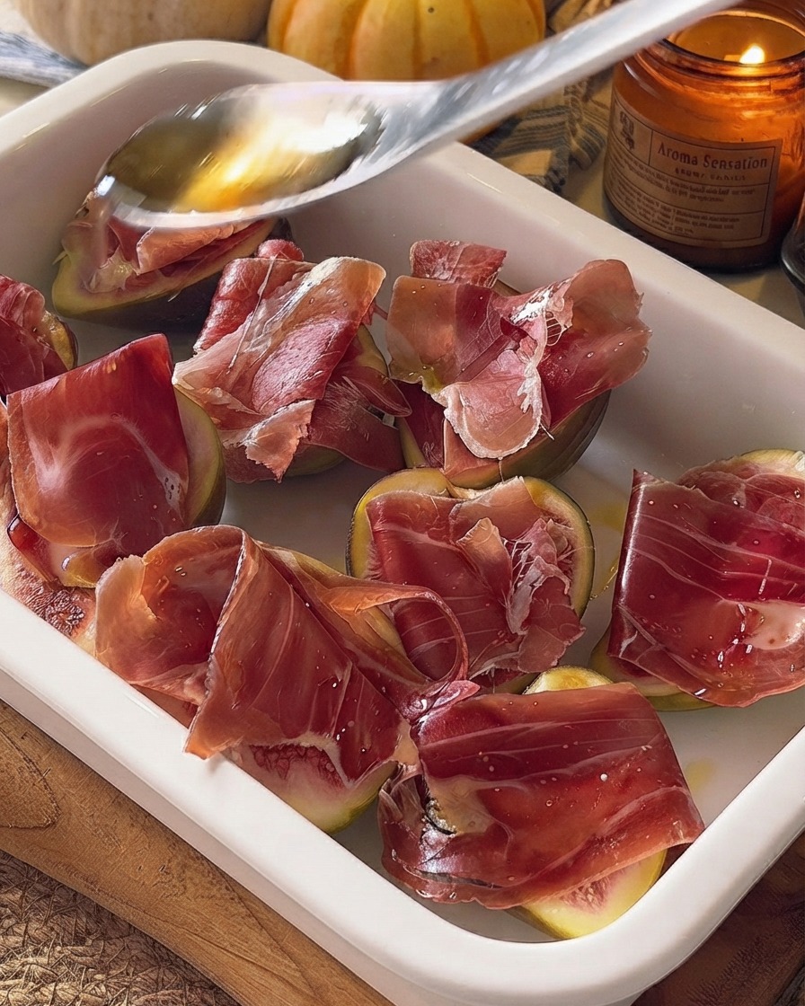 Miel cayendo desde una cuchara sobre los higos y el prosciutto preparados en una fuente de horno.