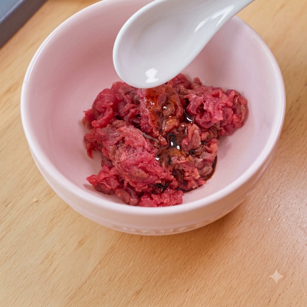 Una cuchara blanca agregando almidón a un tazón rosado lleno de carne cruda en cubitos, salsa de soya y aceite.