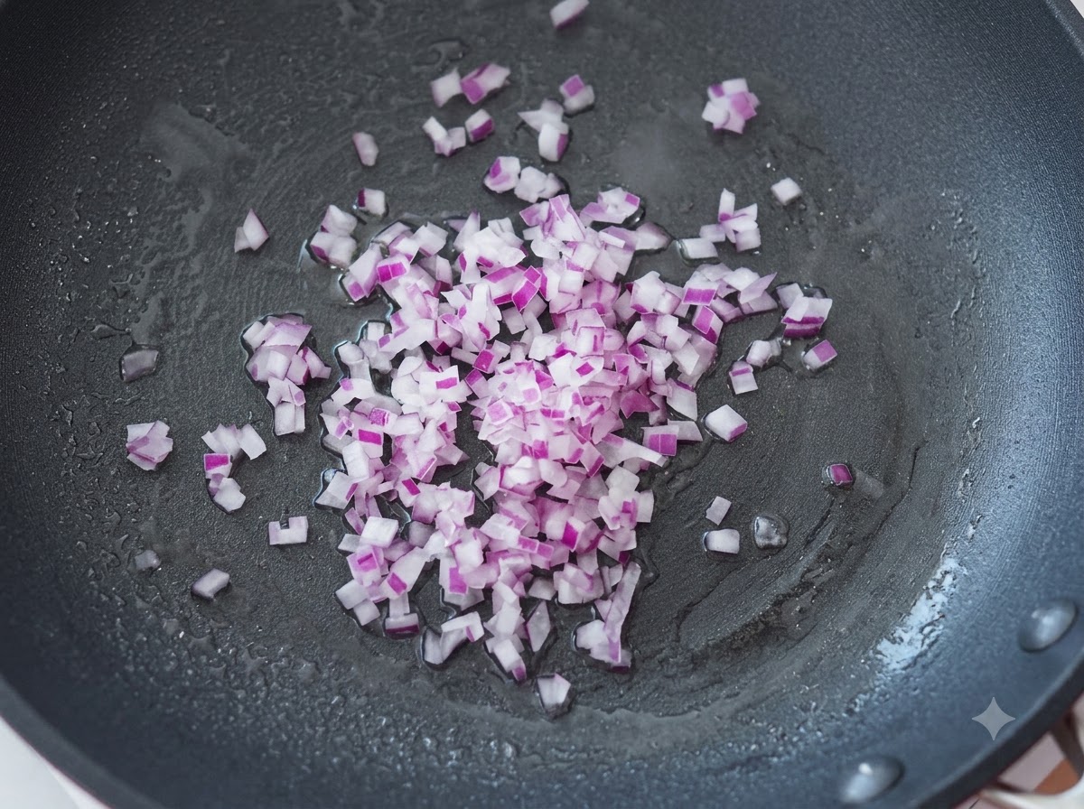 Cebollas moradas finamente picadas salteándose en una sartén caliente con aceite.
