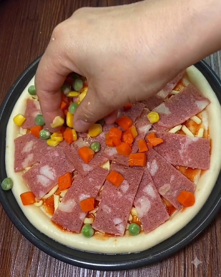 Lonchas de tocino, maíz dulce y trozos de verduras colocándose sobre la pizza.