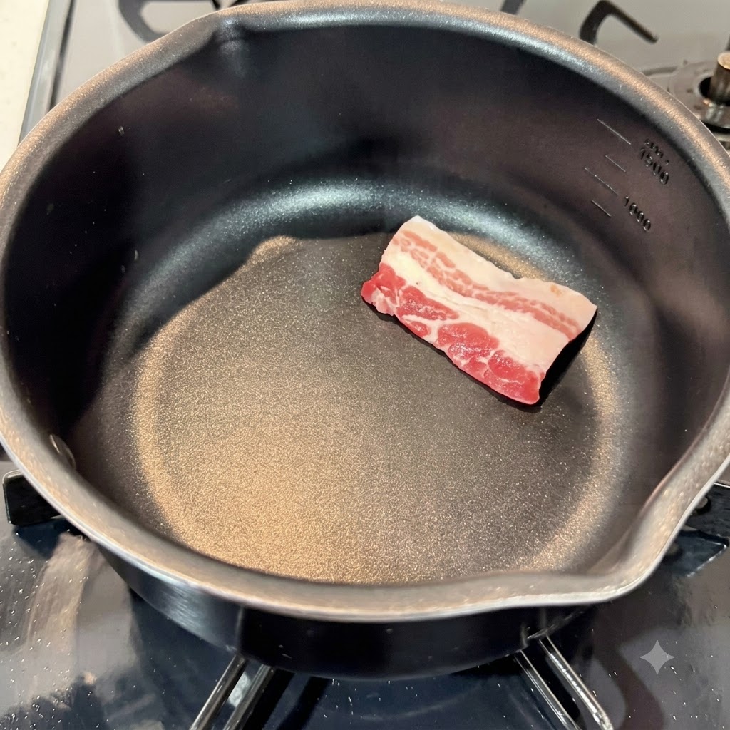 Rebanadas crudas de panceta de cerdo dispuestas en una olla de cocina negra vacía.