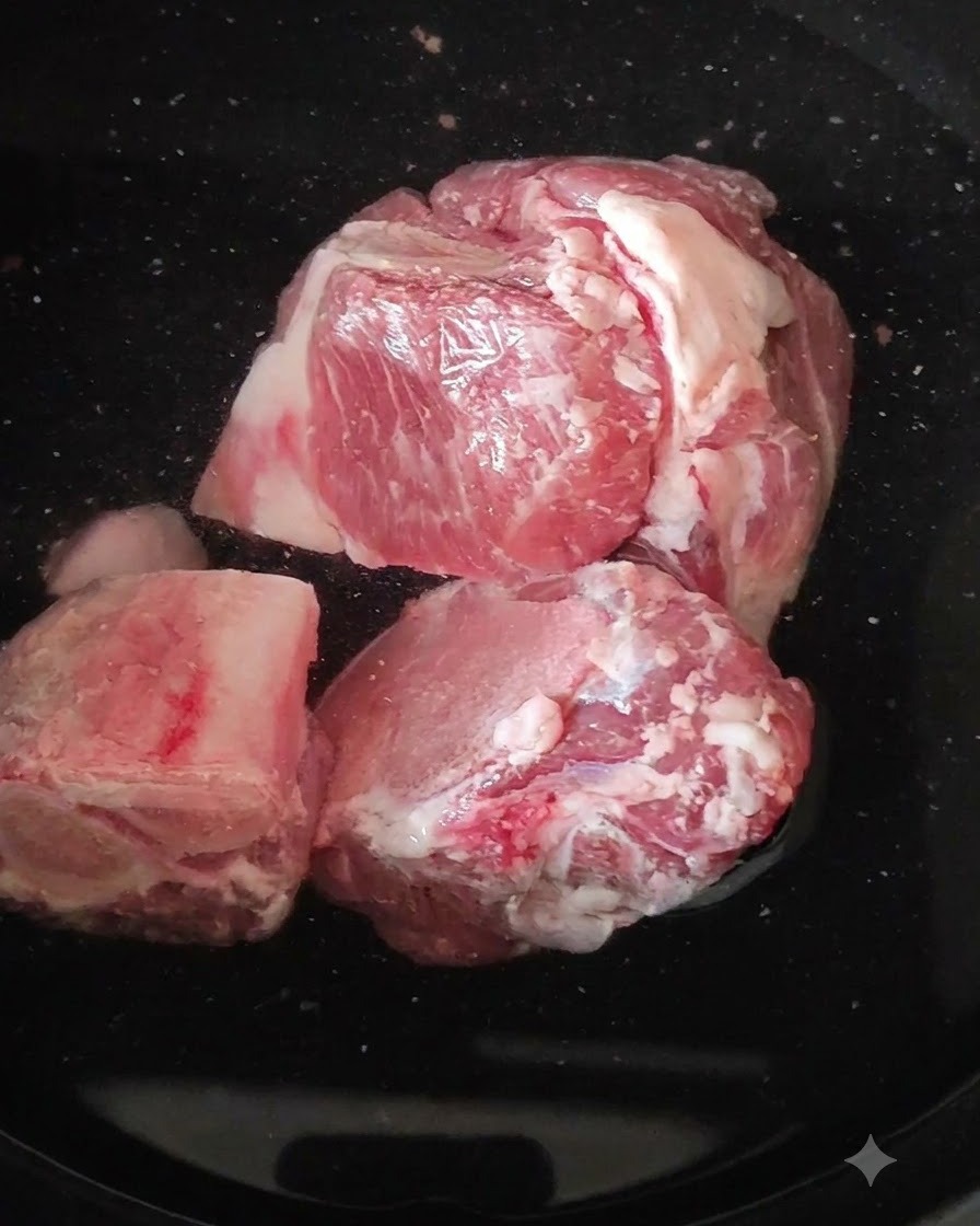 Huesos de pierna de cerdo crudos en una olla con agua hirviendo.