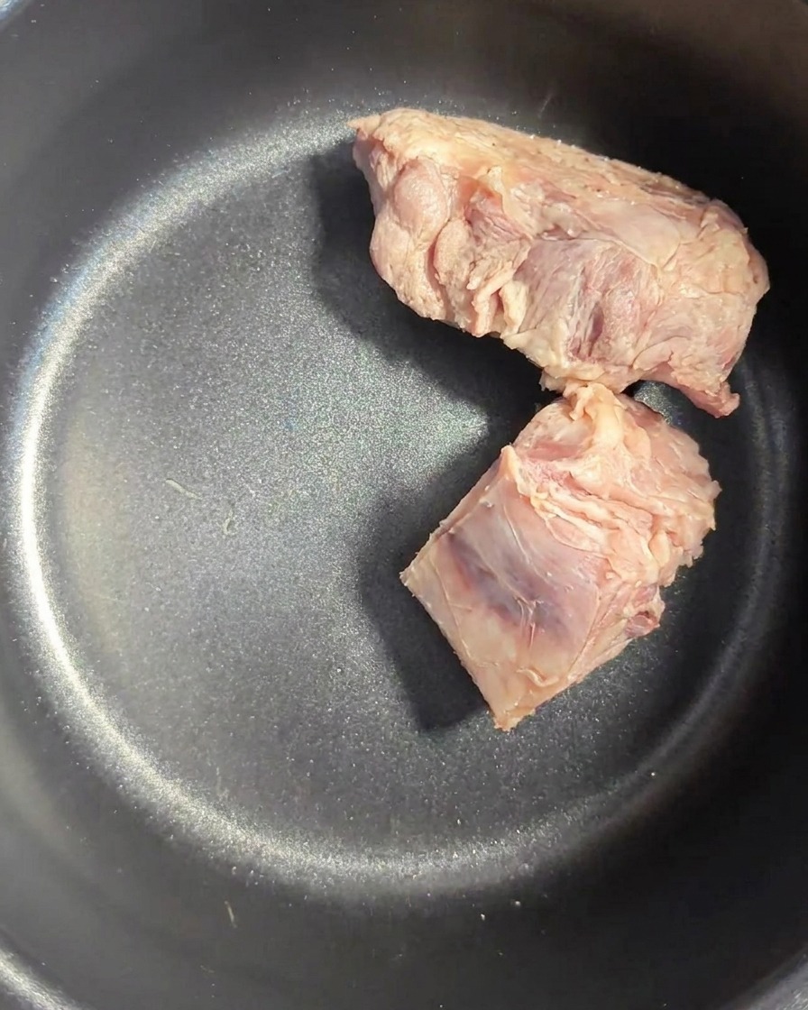 Huesos de cerdo enjuagados dentro de la olla oscura de una arrocera.