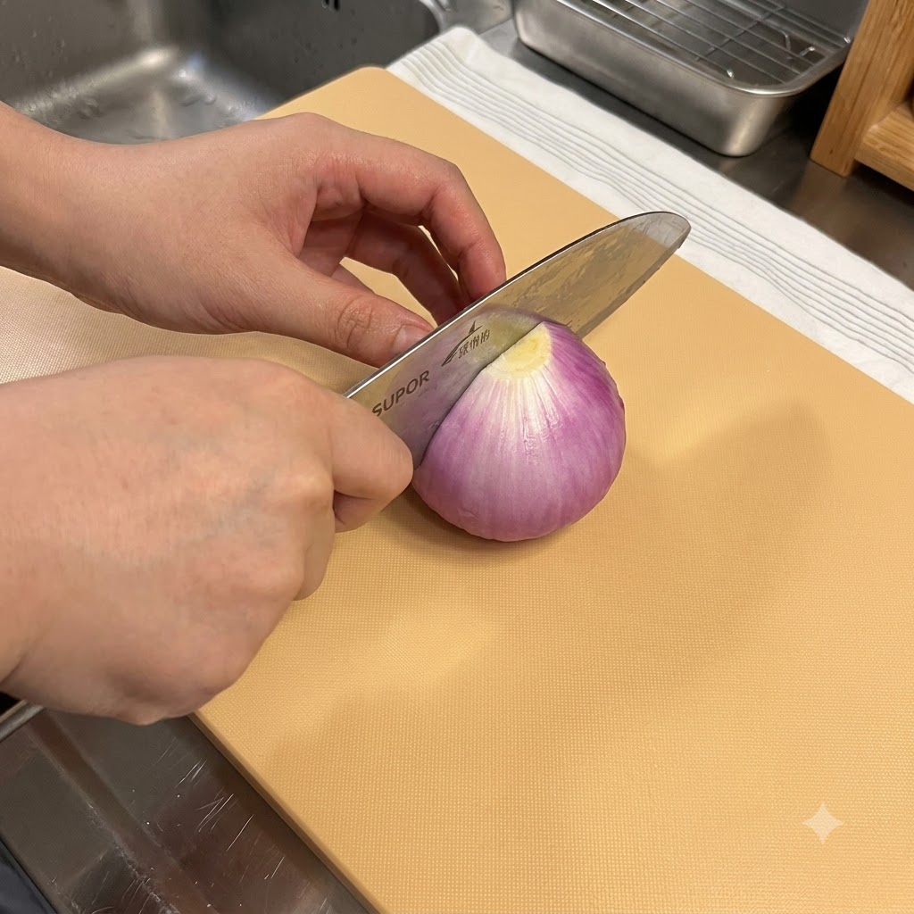 Un cuchillo de cocina cortando una cebolla morada sobre una tabla de cortar de madera.