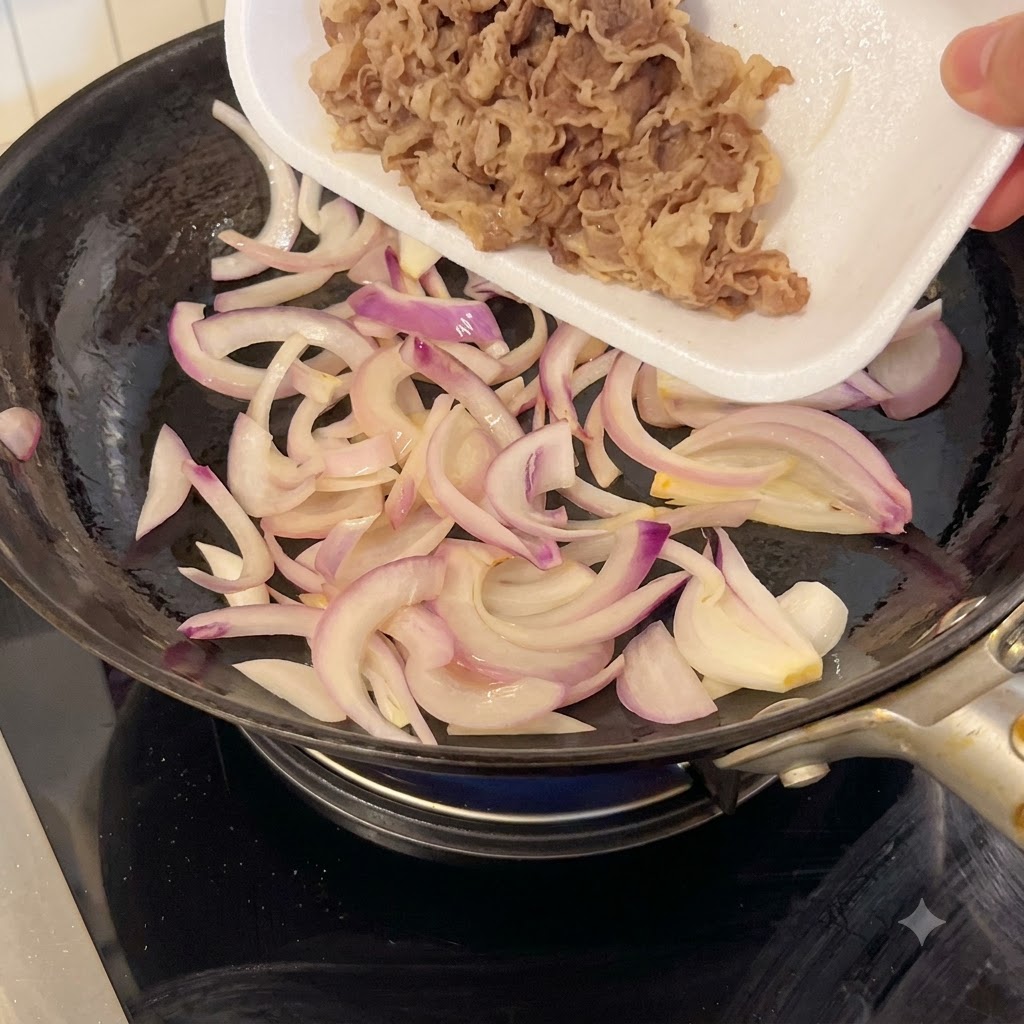 Ternera cortada finamente siendo vertida desde una bandeja de espuma blanca a una sartén con cebollas moradas salteadas.