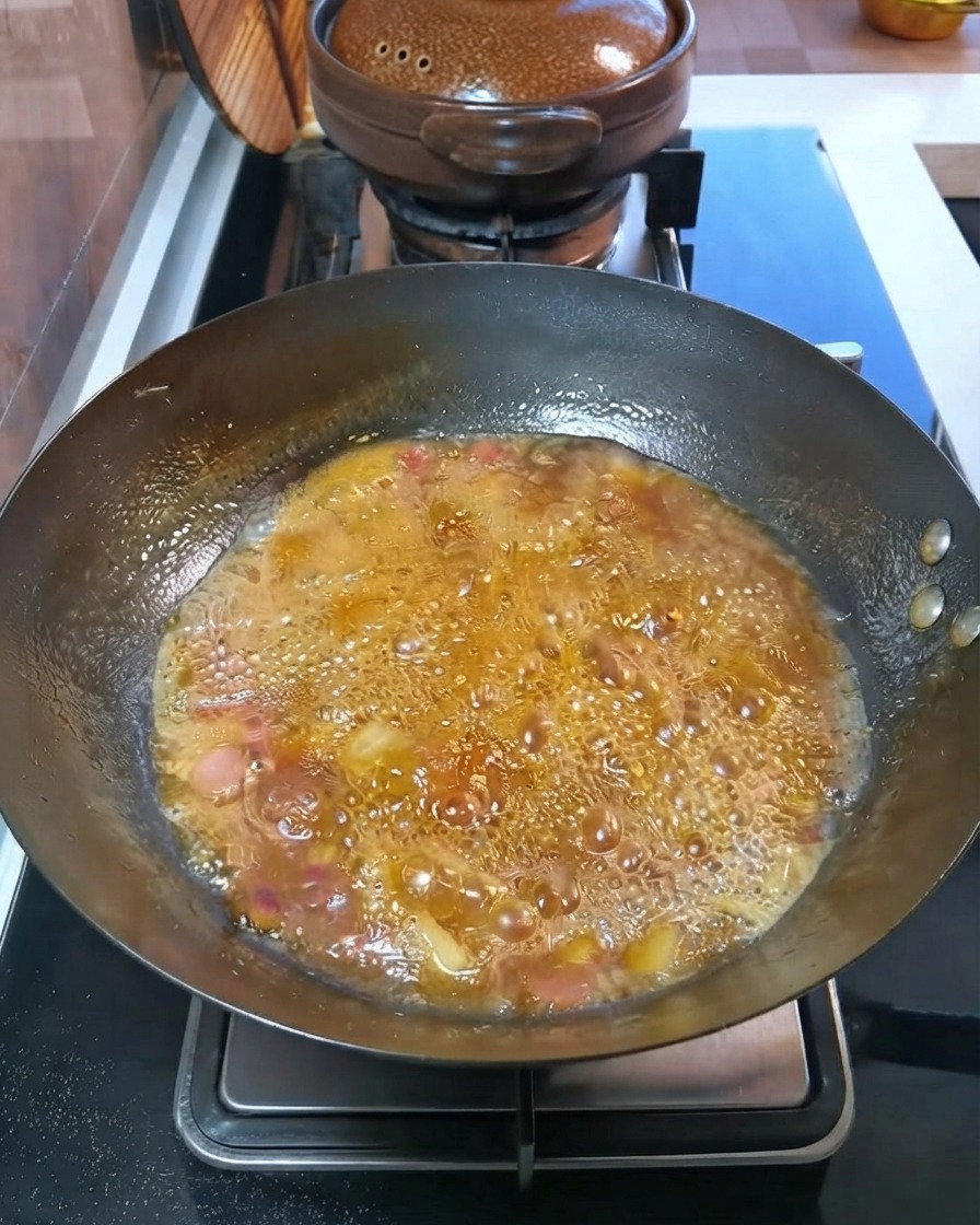 Patatas y zanahorias en cubitos hirviendo a fuego lento en un caldo burbujeante dentro del wok.