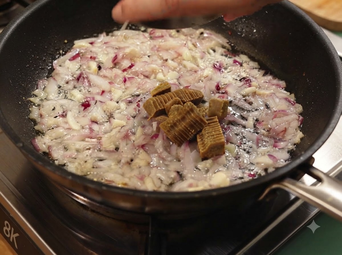 Bloques de curry cortados añadidos a las cebollas y ajos cocidos en una sartén.
