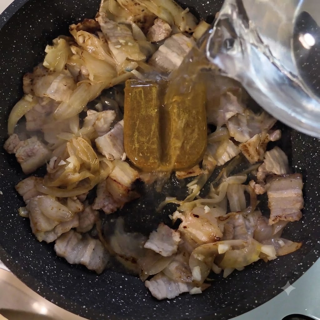 Agua siendo vertida desde un recipiente en la sartén sobre la pasta de curry y la carne.