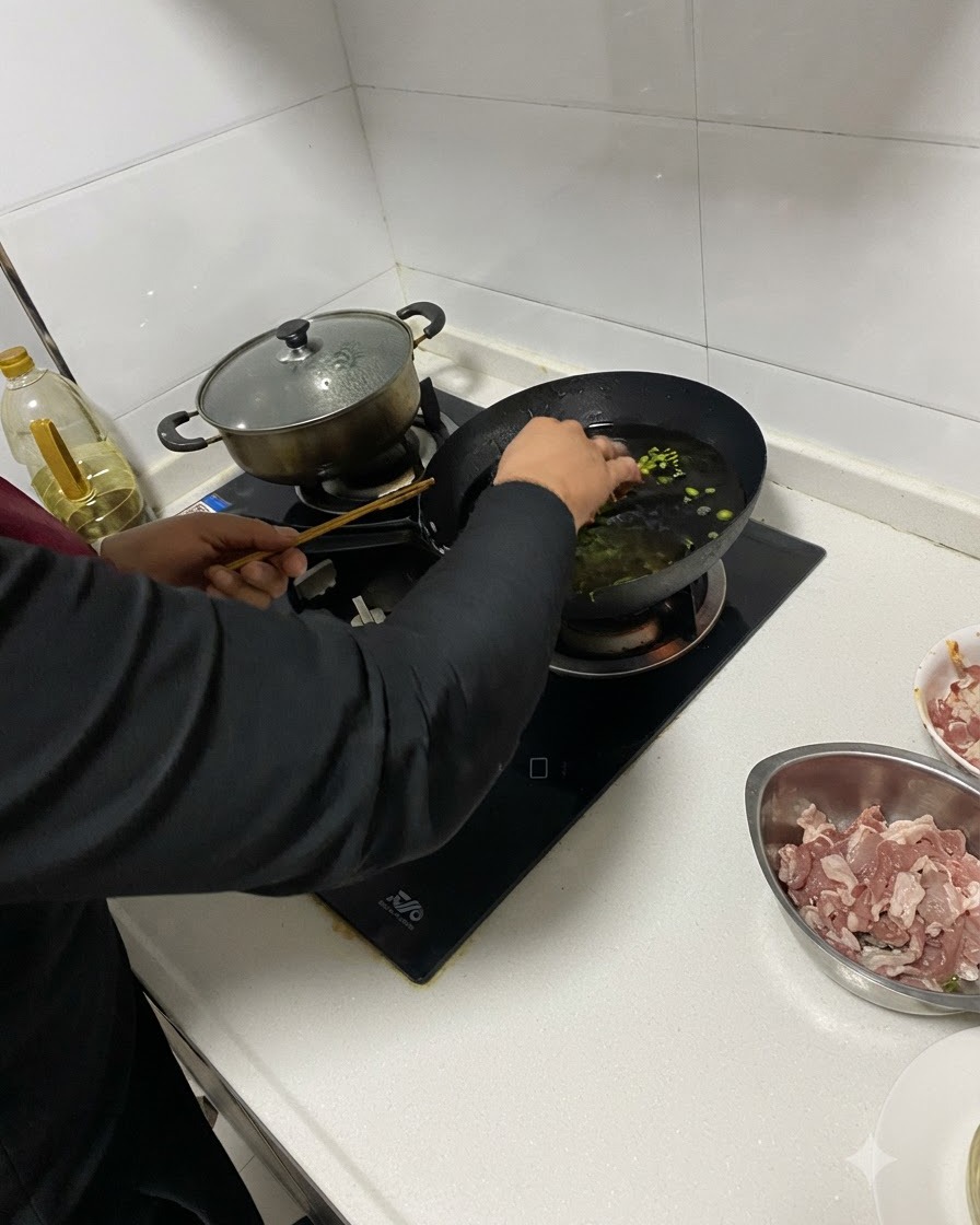 Aromáticos picados siendo añadidos al aceite caliente en un wok usando palillos.