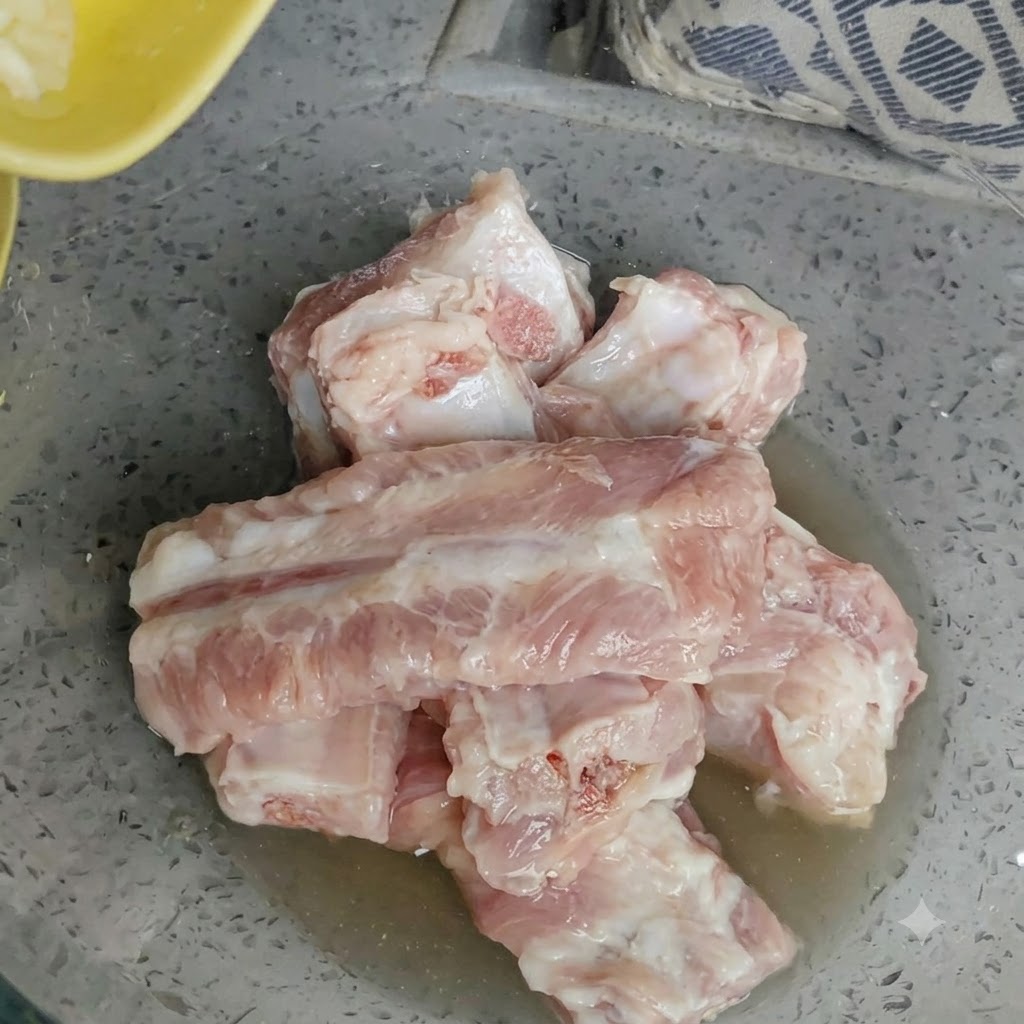 Tazón con costillas de cerdo crudas y ajo recién picado esparcido por encima.