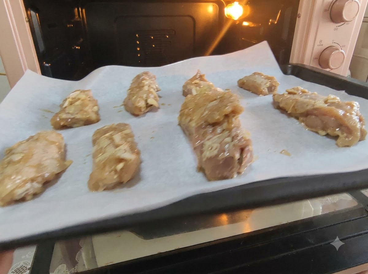Costillas de cerdo marinadas ordenadas sobre papel pergamino en una bandeja de horno.