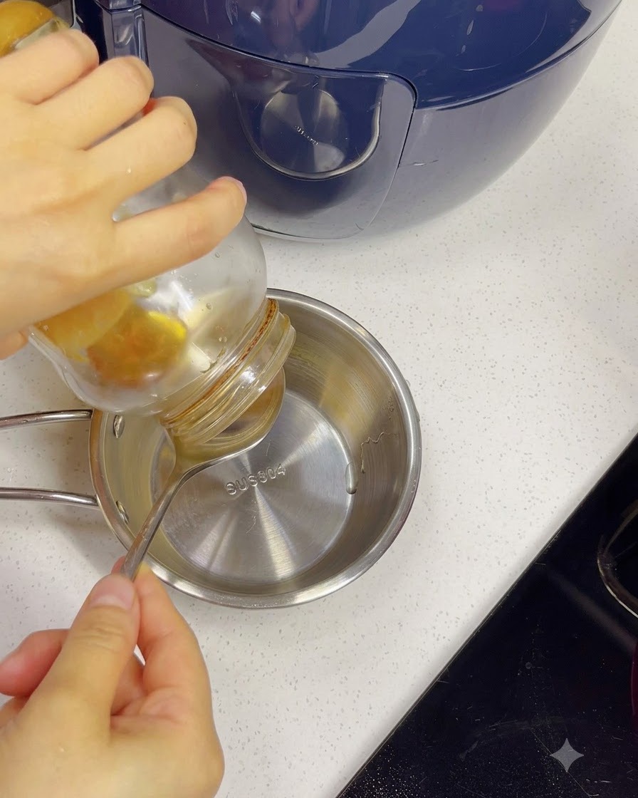 Miel vertiéndose desde un frasco a un tazón pequeño de acero inoxidable con agua usando una cuchara.