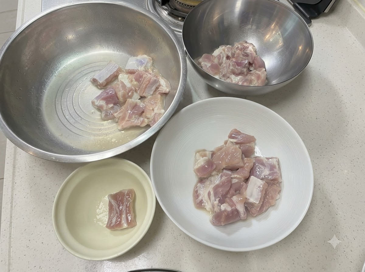 Trozos de costillas de cerdo dispuestos en varios boles de metal y cerámica en una encimera blanca.