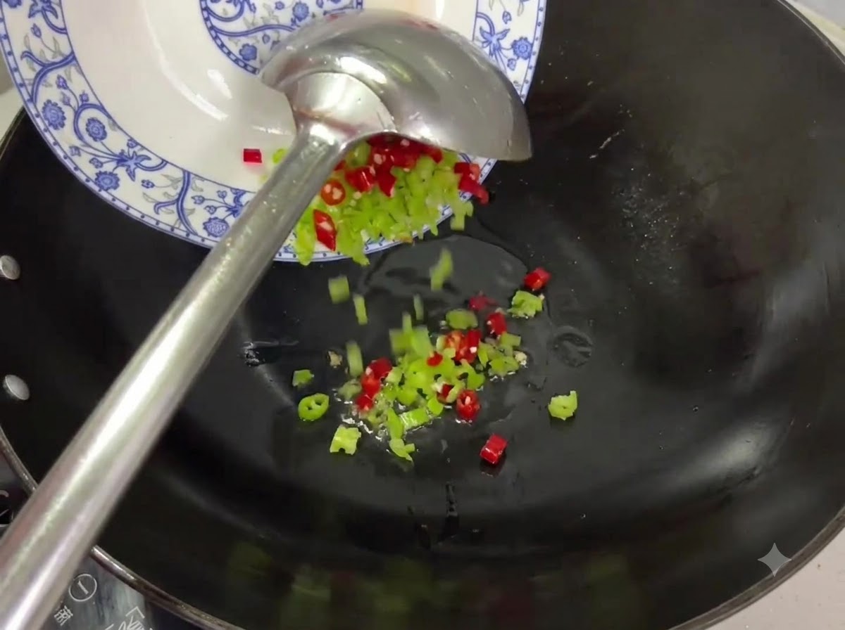 Trozos de chile rojo y verde siendo vertidos desde un plato a un wok con aceite.