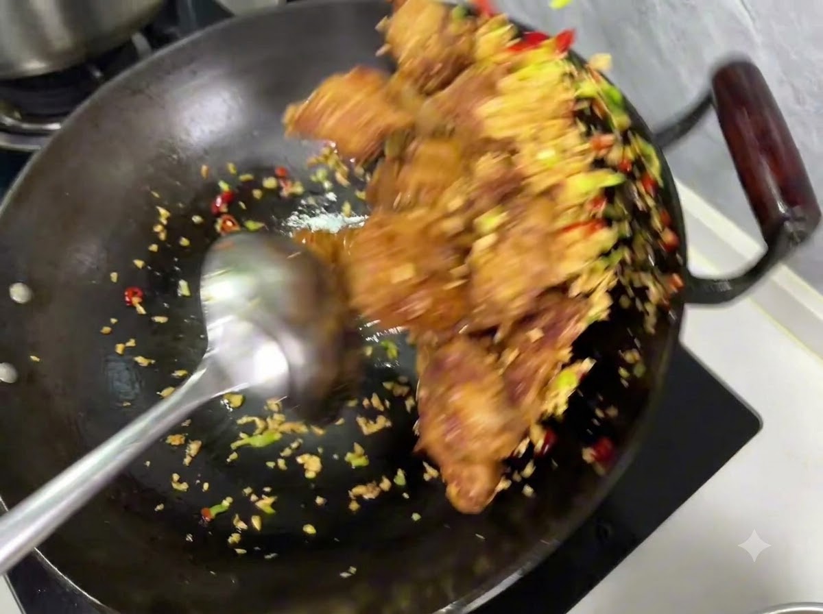 Sazonador de sal y pimienta siendo espolvoreado sobre la mezcla de costillas y ajo dentro de un wok.