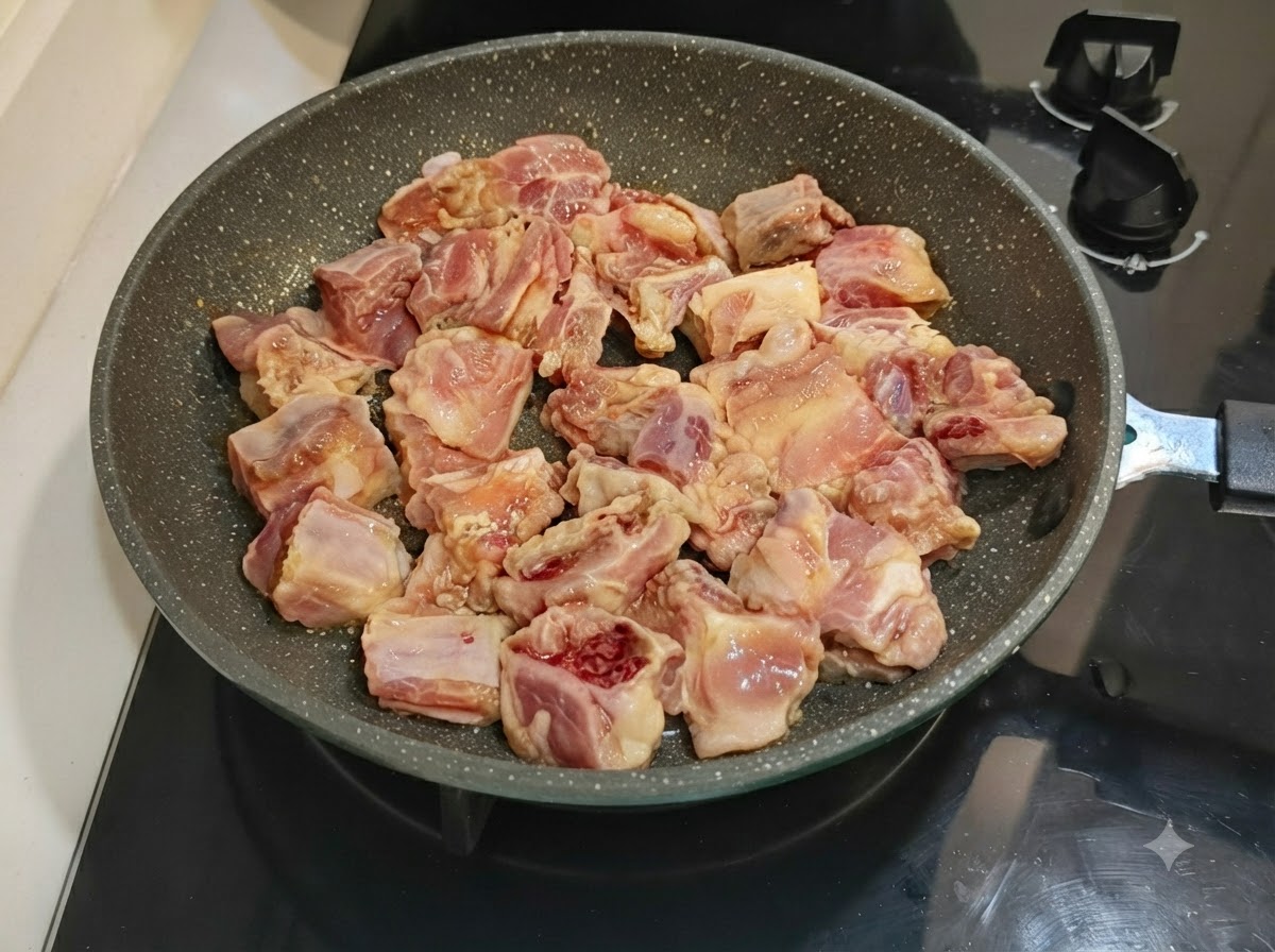 Costillas de cerdo marinadas ordenadamente dispuestas en una sartén moteada sobre una estufa.