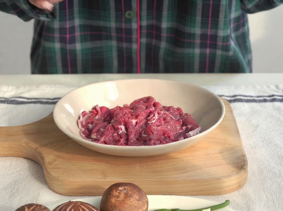 Trozos de solomillo de ternera en un bol poco profundo siendo marinados con salsa de ostras y maicena.