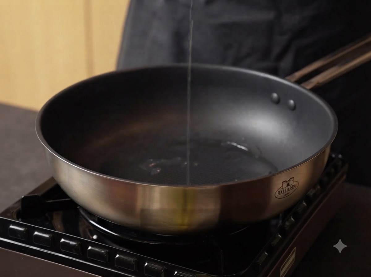 Aceite siendo vertido en una sartén de acero inoxidable caliente en una estufa.