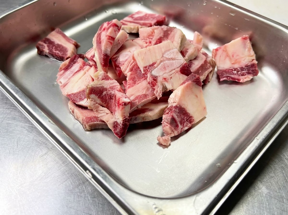 Costillas cortas de res crudas colocadas dentro de un recipiente de metal limpio listas para ser sazonadas.