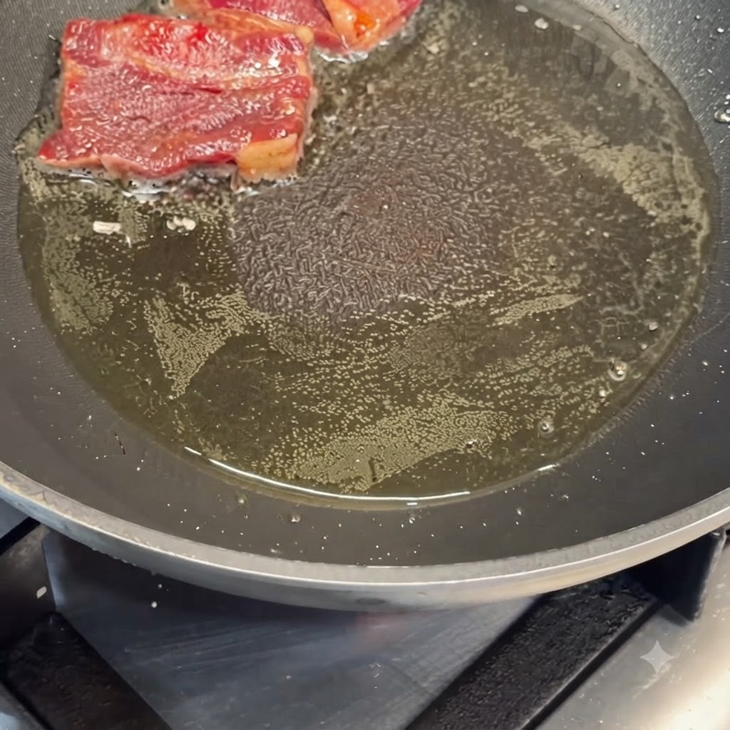 Costillas de res marinadas dorándose en aceite caliente en una sartén.