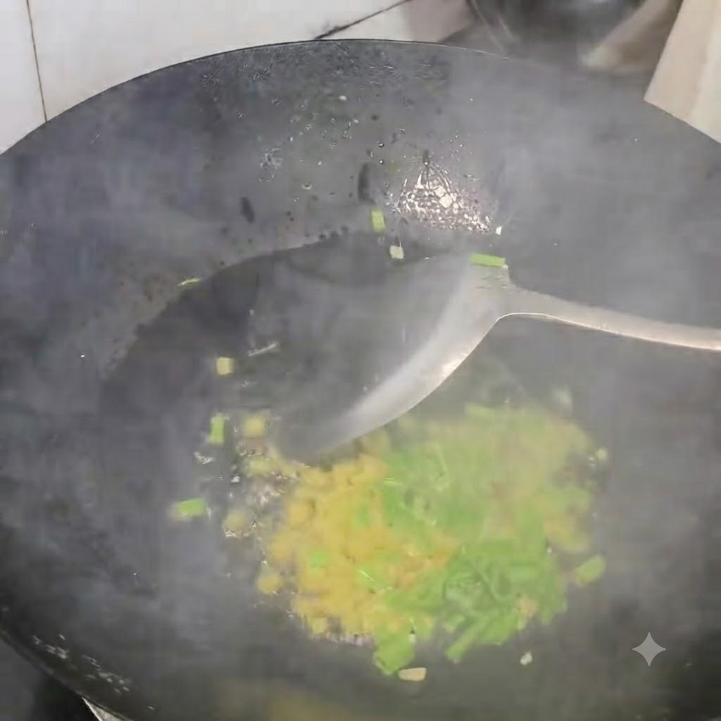 Cebollín, jengibre y ajo picados salteándose en un wok negro caliente con una espátula.