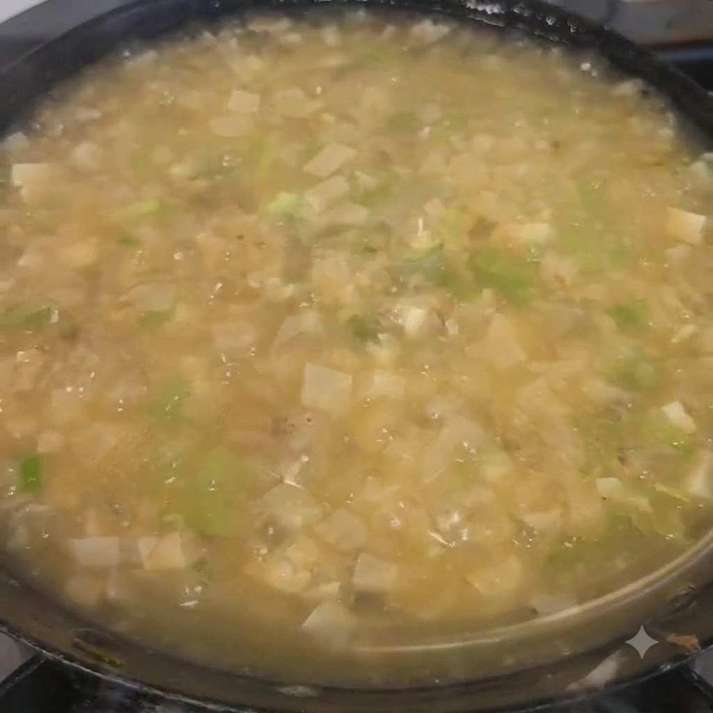 Cilantro picado siendo espolvoreado sobre la sopa terminada en la olla.
