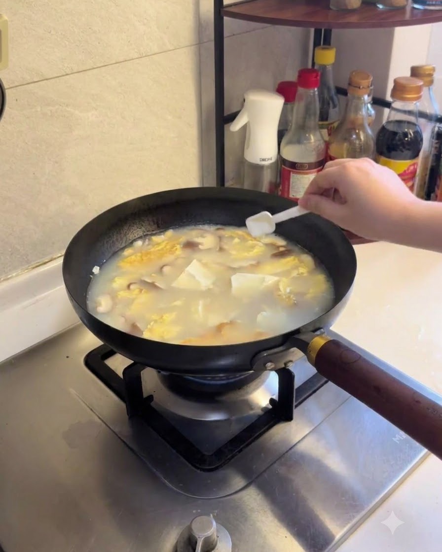Sal y pimienta blanca siendo espolvoreadas en la sopa de tofú y champiñones a fuego lento.