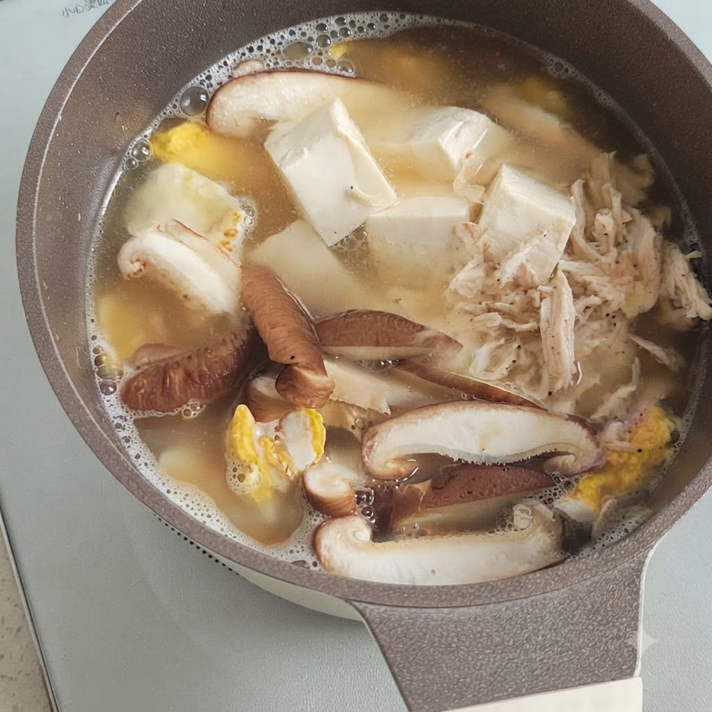 Un pequeño montículo de camarones secos sobre tofu, champiñones y huevo hirviendo a fuego lento en una olla de caldo.