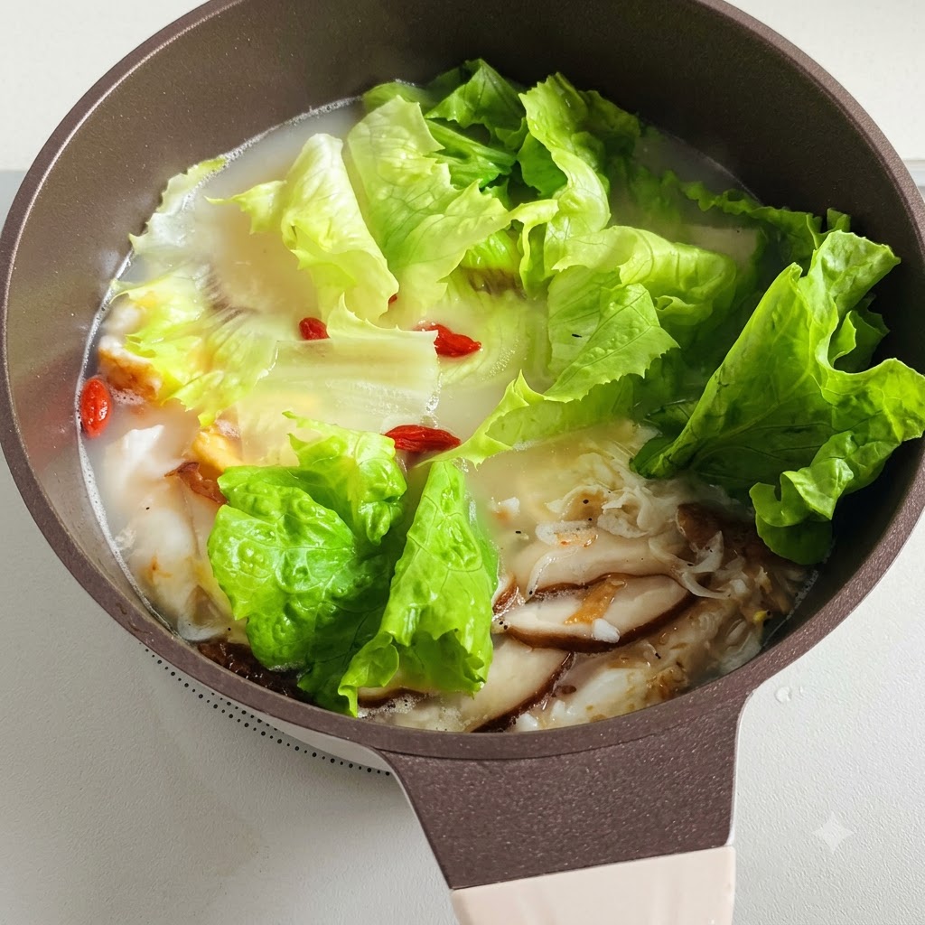 Una olla de sopa a fuego lento con hojas de lechuga y bayas de goji rojas flotando en su interior.