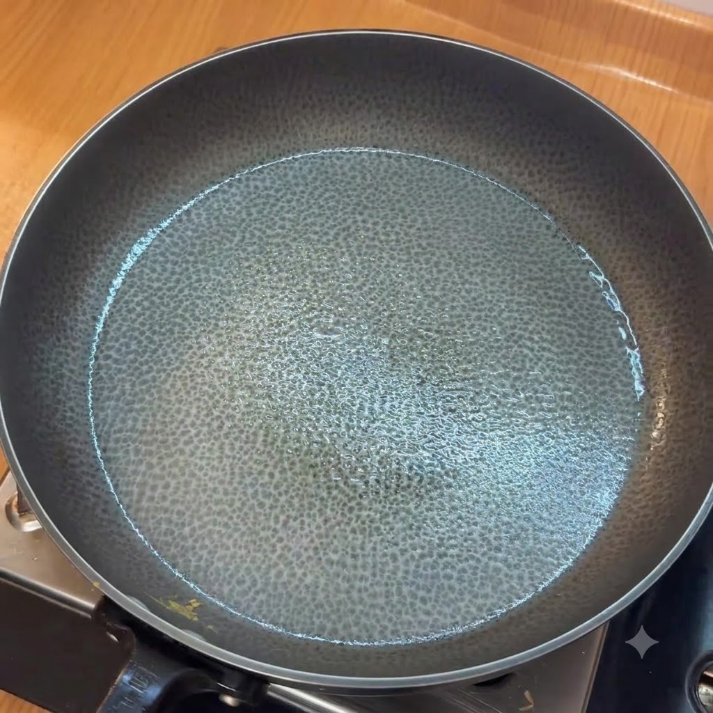 Ajo picado sofriéndose en una sartén engrasada antes de añadir tomates picados.