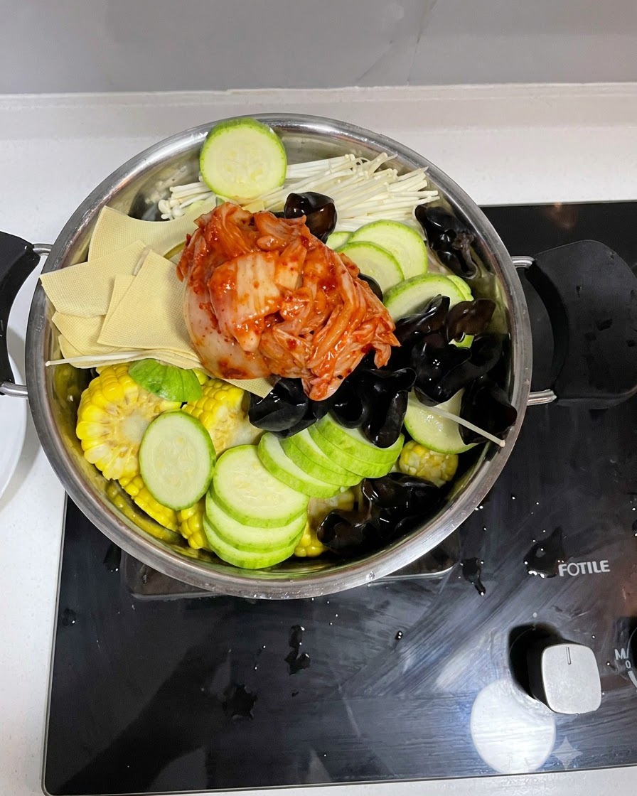Virtiendo la mezcla de salsa preparada sobre los ingredientes en la olla de cocina.