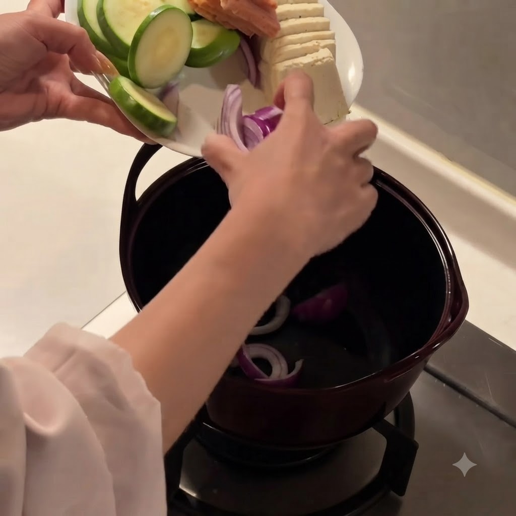 Cebollas rojas cortadas siendo colocadas en el fondo de una olla de cocina oscura.