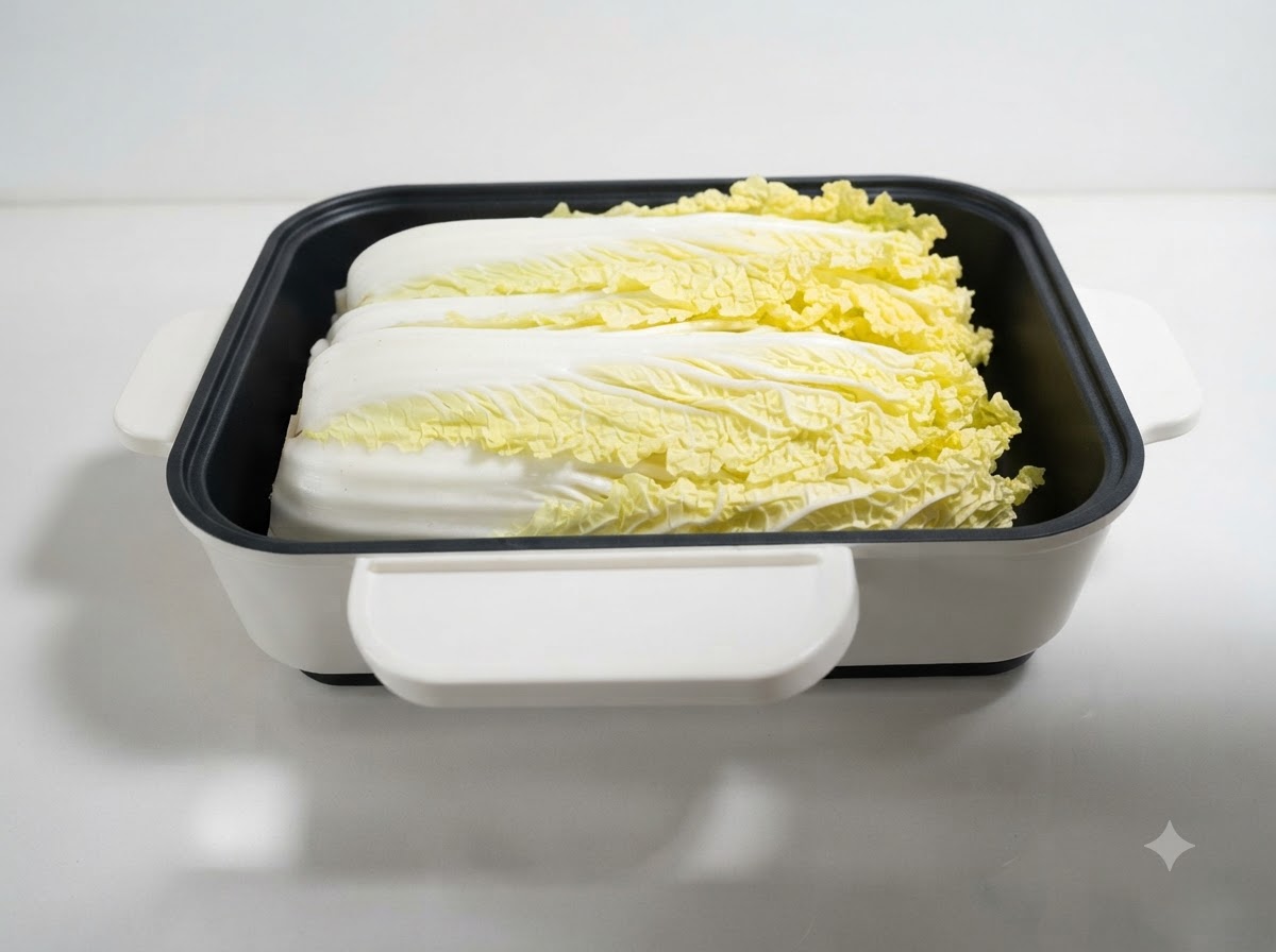 Hojas de repollo colocadas ordenadamente dentro de una olla poco profunda cuadrada blanca.