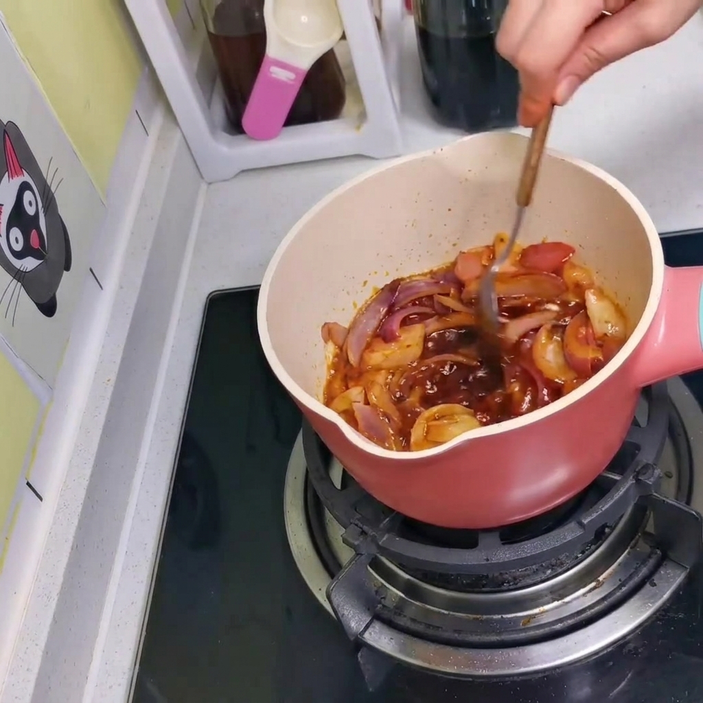 La salsa, las cebollas y el kimchi siendo mezclados juntos en la olla con una cuchara.