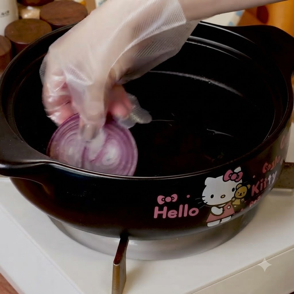 Rodajas de cebolla roja colocadas en el fondo de una olla de cocción negra.
