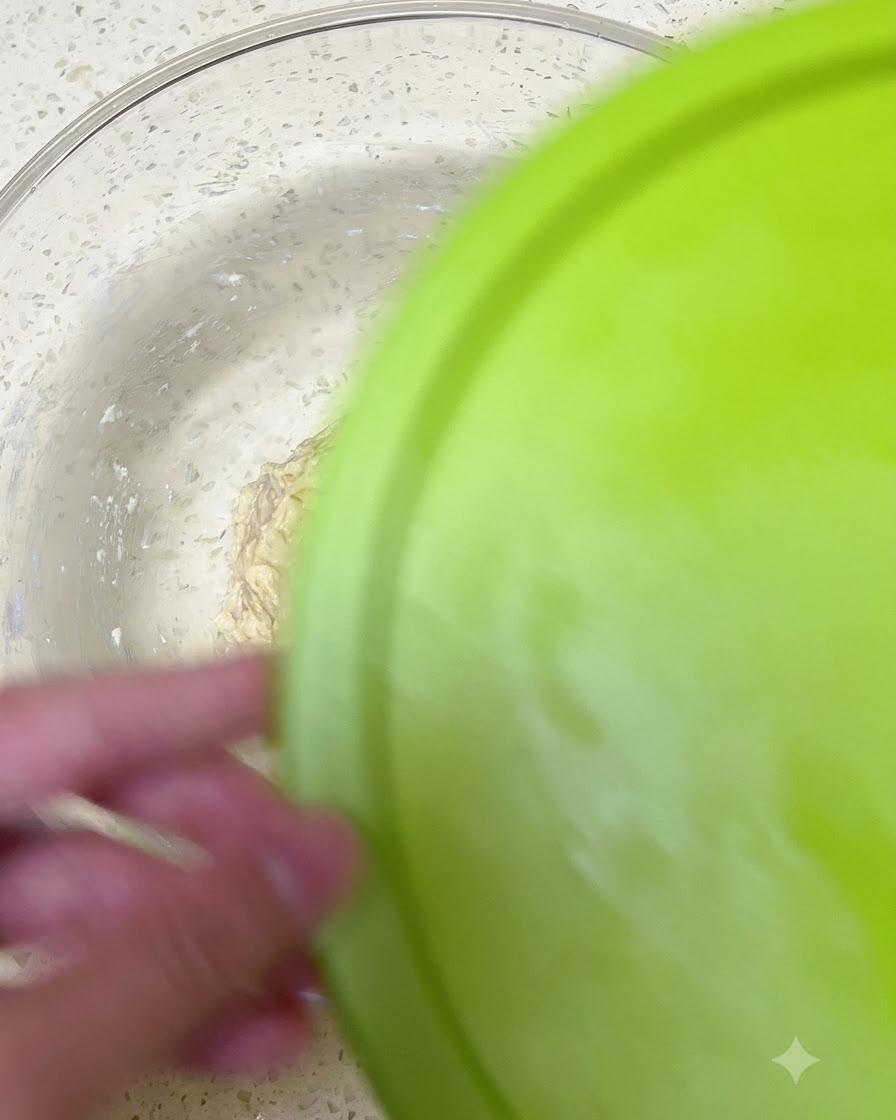Un tazón de masa siendo sellado con una tapa verde para refrigeración.