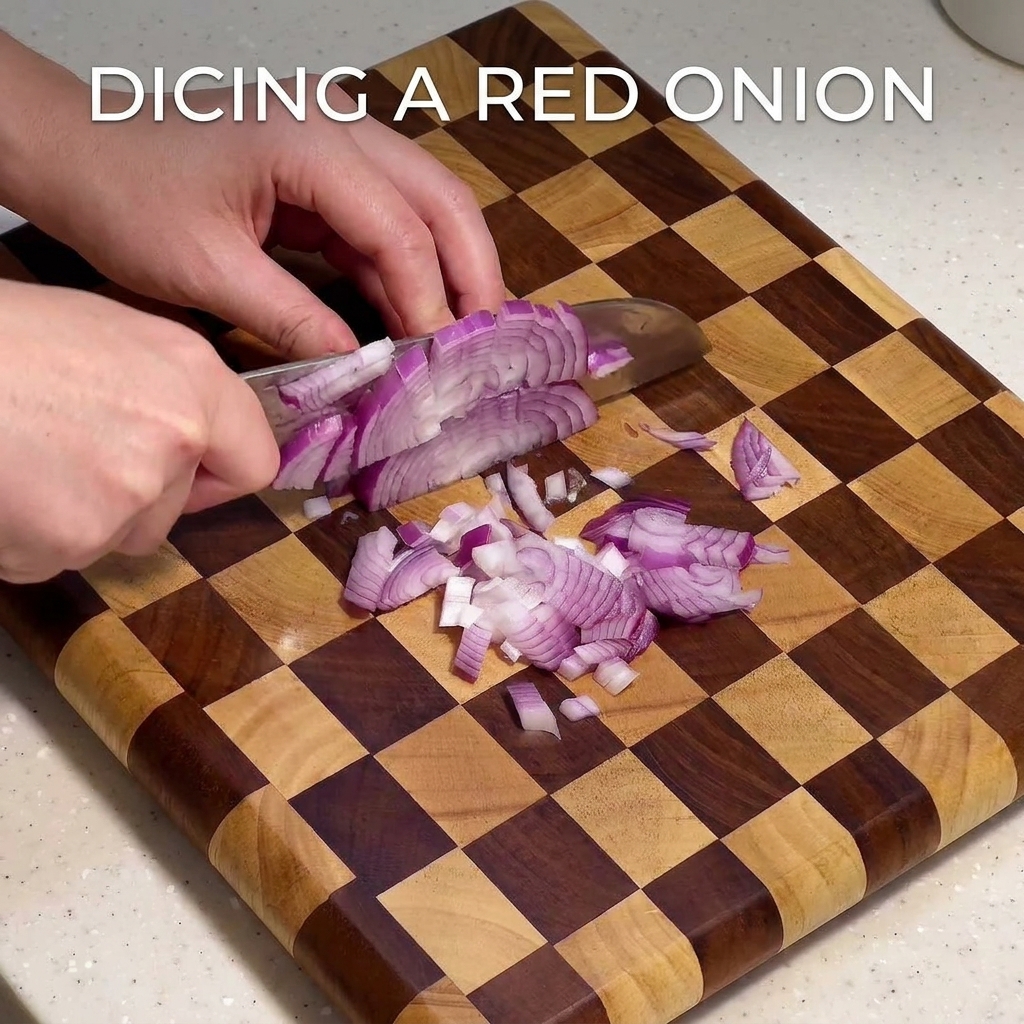 Un primer plano de una cebolla morada picándose finamente en una tabla de cortar de madera a cuadros con un cuchillo de chef.