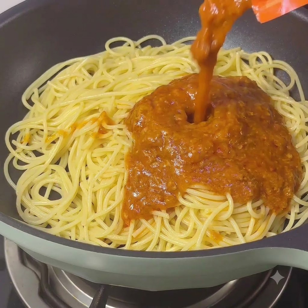 Rica salsa boloñesa clásica siendo vertida sobre los fideos de espagueti en una sartén.