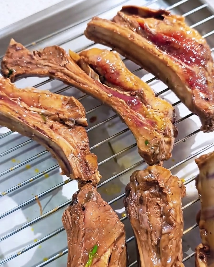 Costillas de cerdo marinadas colocadas ordenadamente sobre una rejilla metálica de horno.
