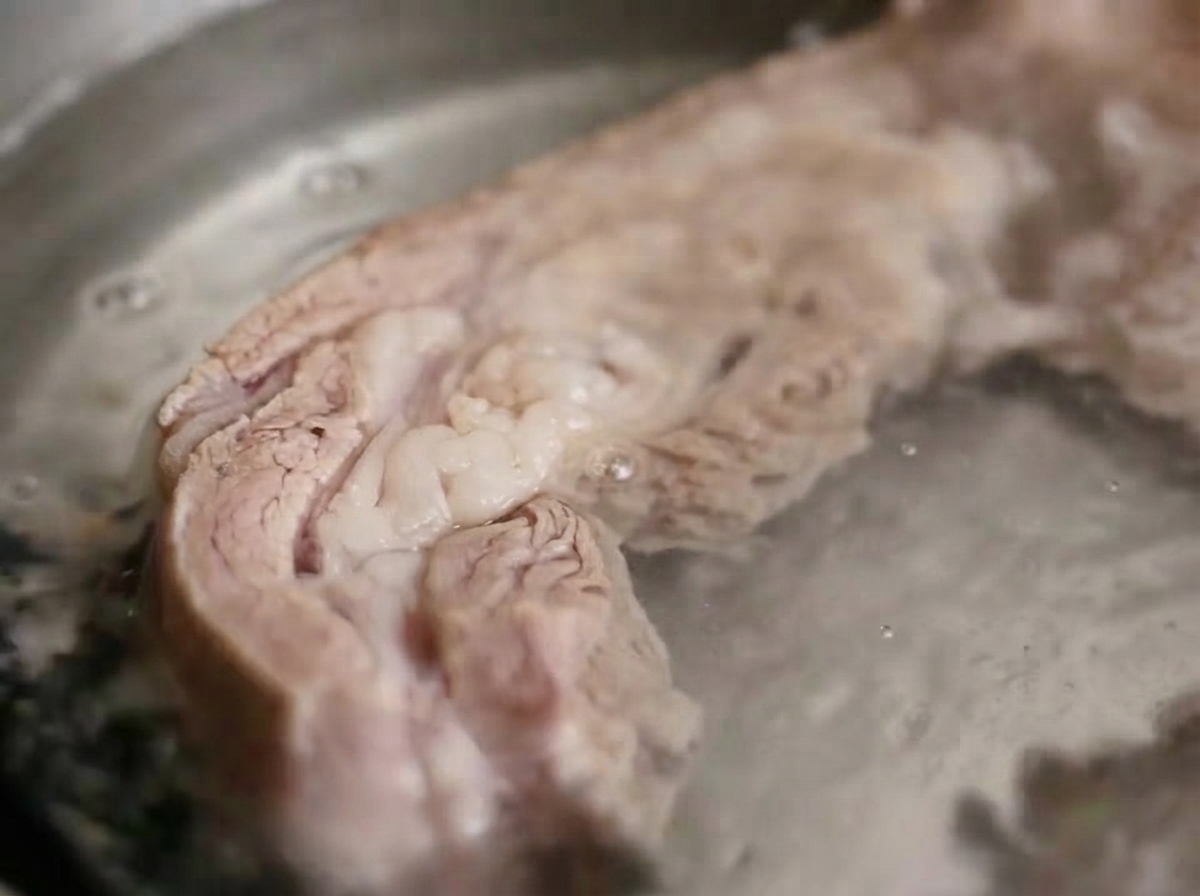 Costillas de cerdo hirviendo en agua caliente en una olla de cocina.