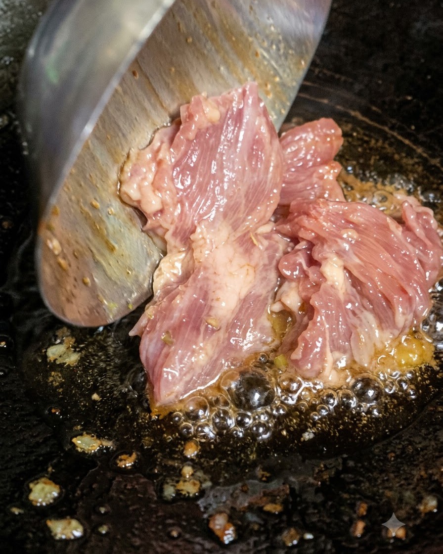 Carne picada cruda siendo añadida con un cucharón al aceite caliente y burbujeante en un wok.