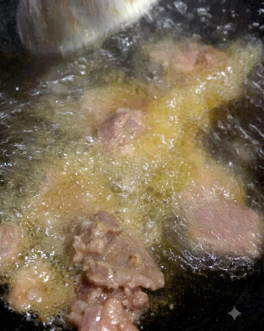 Carne cocinándose en aceite caliente con condimentos burbujeando en la sartén.