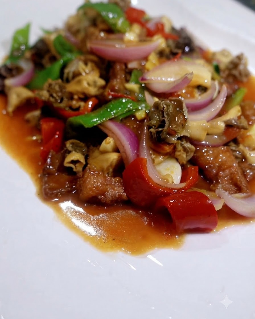 Una mezcla terminada de setas, pimientos rojos, pimientos verdes y cebolla en una salsa sabrosa sobre un plato blanco.