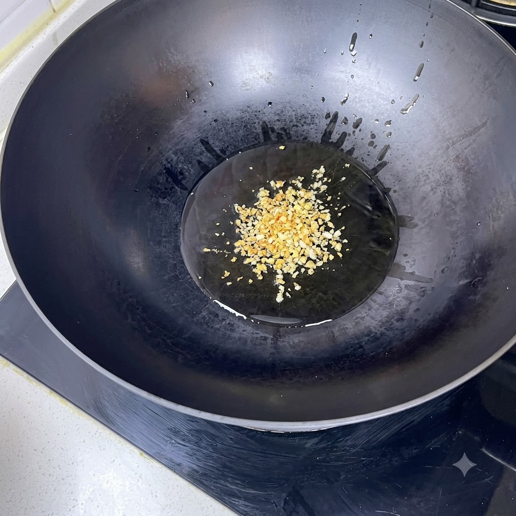 Ajo picado friéndose en aceite caliente dentro de un wok negro.